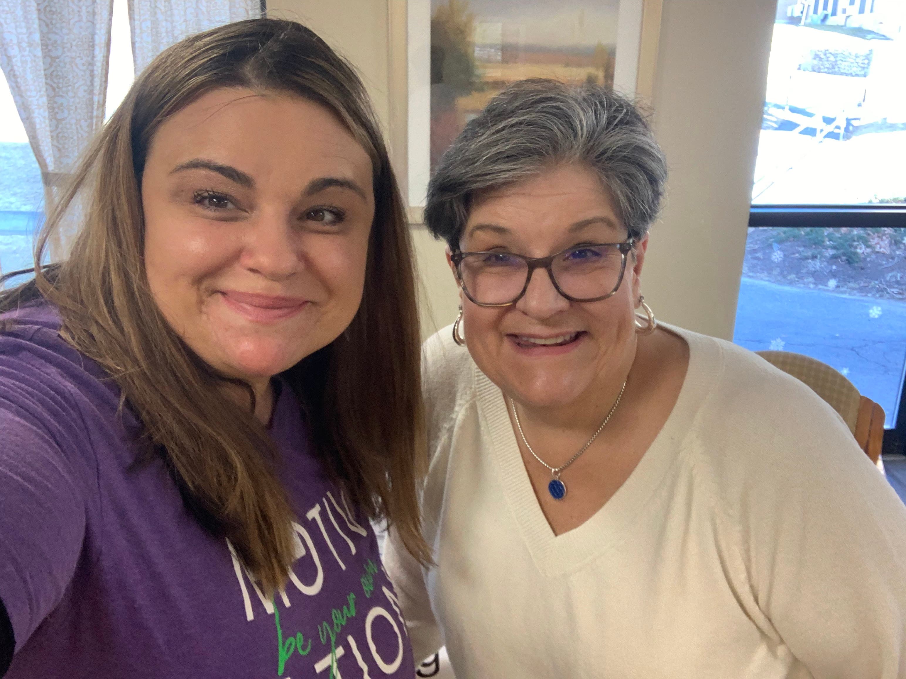 Two family caregivers smiling together during a support visit