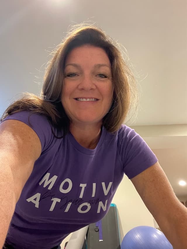 Kathy Clark wearing a purple Motivation shirt, ready to help clients achieve their fitness goals